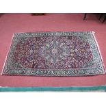 A Kashan Style Rug, the wine red field with central medallion bordered by scrolling plant forms, the