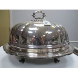 A Plated Meat Dish and Dome, the base of shaped oval form, raised on four scroll feet, the dome with