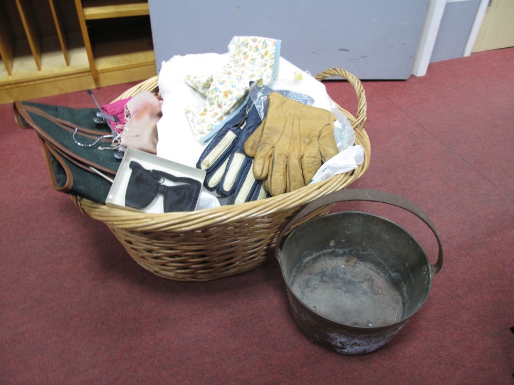 Linens, gloves, brass jam pan, etc., in wicker basket.