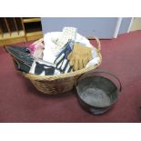 Linens, gloves, brass jam pan, etc., in wicker basket.