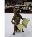 A Bergman Style Cold Painted Comic Cast Model Dog, seated on a chamber pot reading a paper,