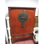 A Chinese Red Lacquer Cabinet, the twin panelled doors with large circular bronzed lock plate