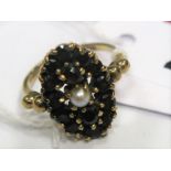 A 9ct Gold Garnet and Pearl Set Cluster Ring, of oval design claw set throughout.