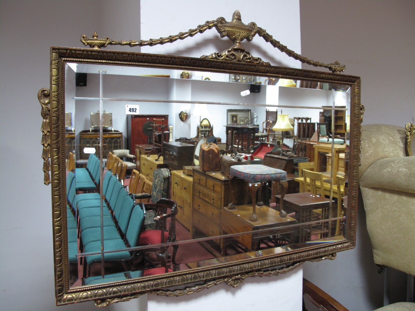 A Bevelled Rectangular Wall Mirror, in gilt frame, featuring vases and swags, 98cm wide.