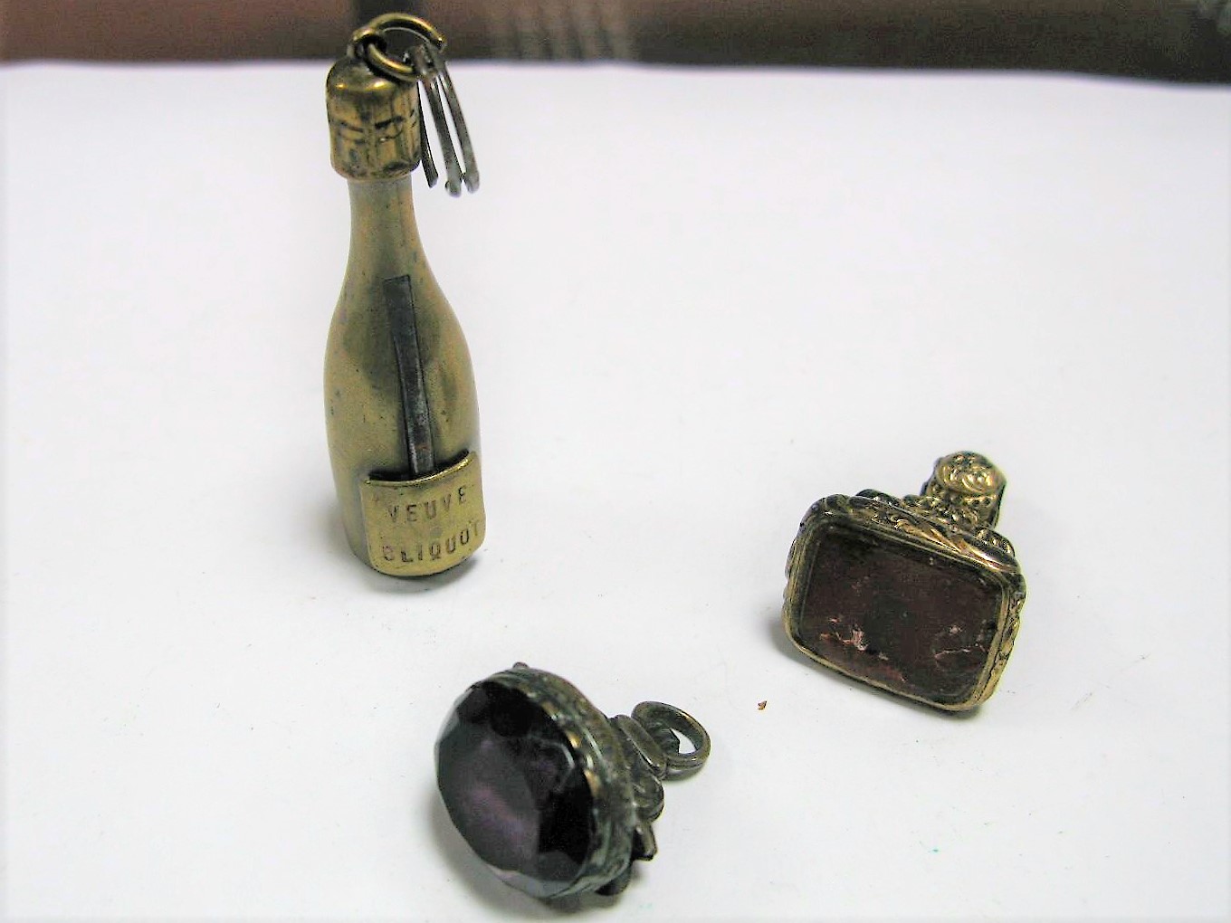 A Novelty Cigar Cutter, as a champagne bottle "Veuve Cliquot"; together with a hardstone inset