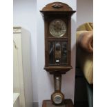 A 1940's Oak and Mahogany Wall Clock, with a silvered dial, glazed door with bevelled panels,