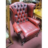A XX Century Red Leather Armchair, with button back and stud decoration, on small cabriole legs.