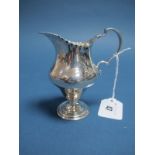 A Hallmarked Silver Jug, (marks rubbed) Chester, with wavy edge and leaf capped scroll handle, on