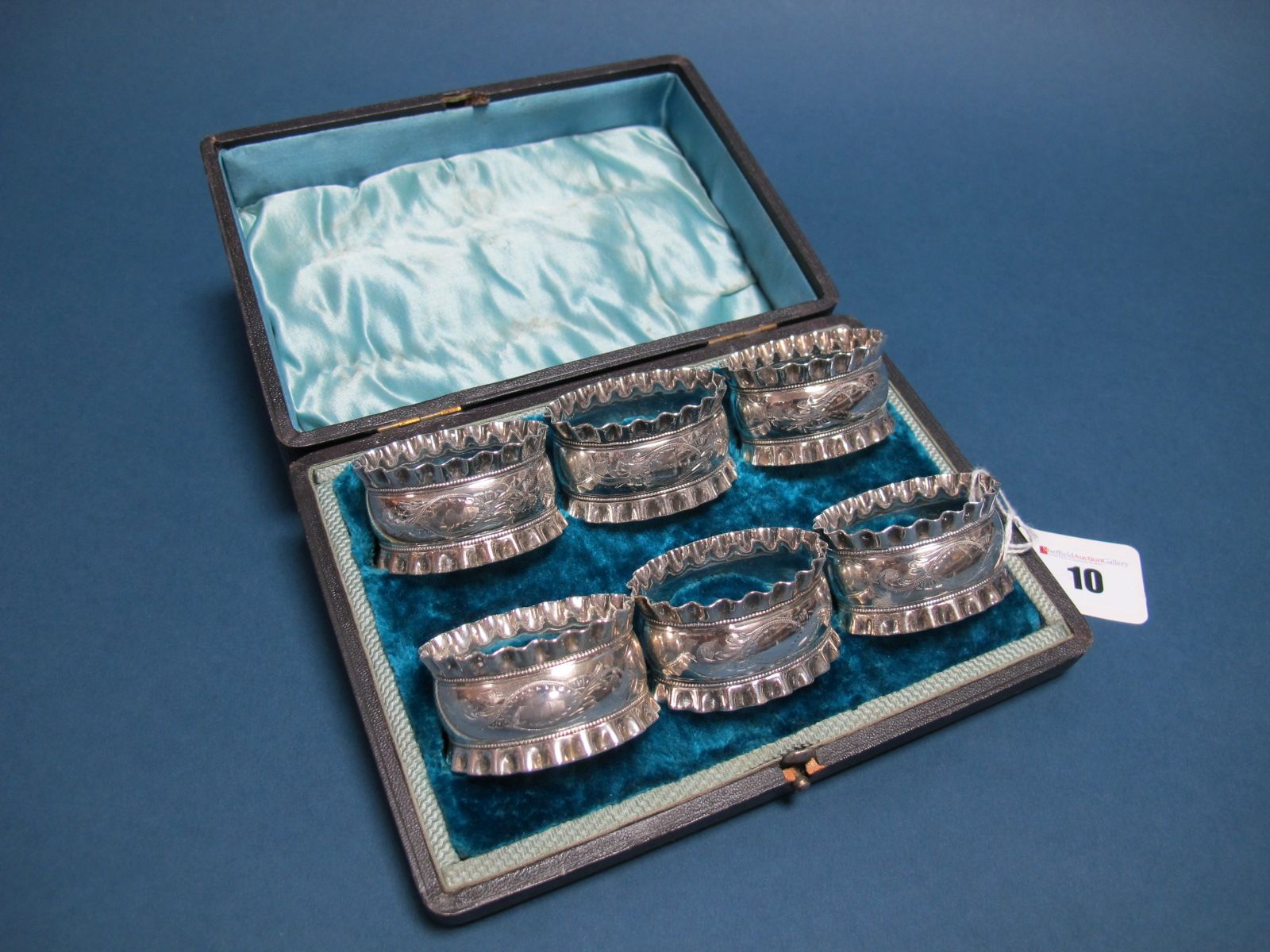 A Set of Six Napkin Rings, each of oval form with wavy edge and engraved leaf scroll detail,