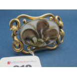 A XIX Century Hairwork Mourning Brooch, the central oval glazed panel enclosing hairwork, within