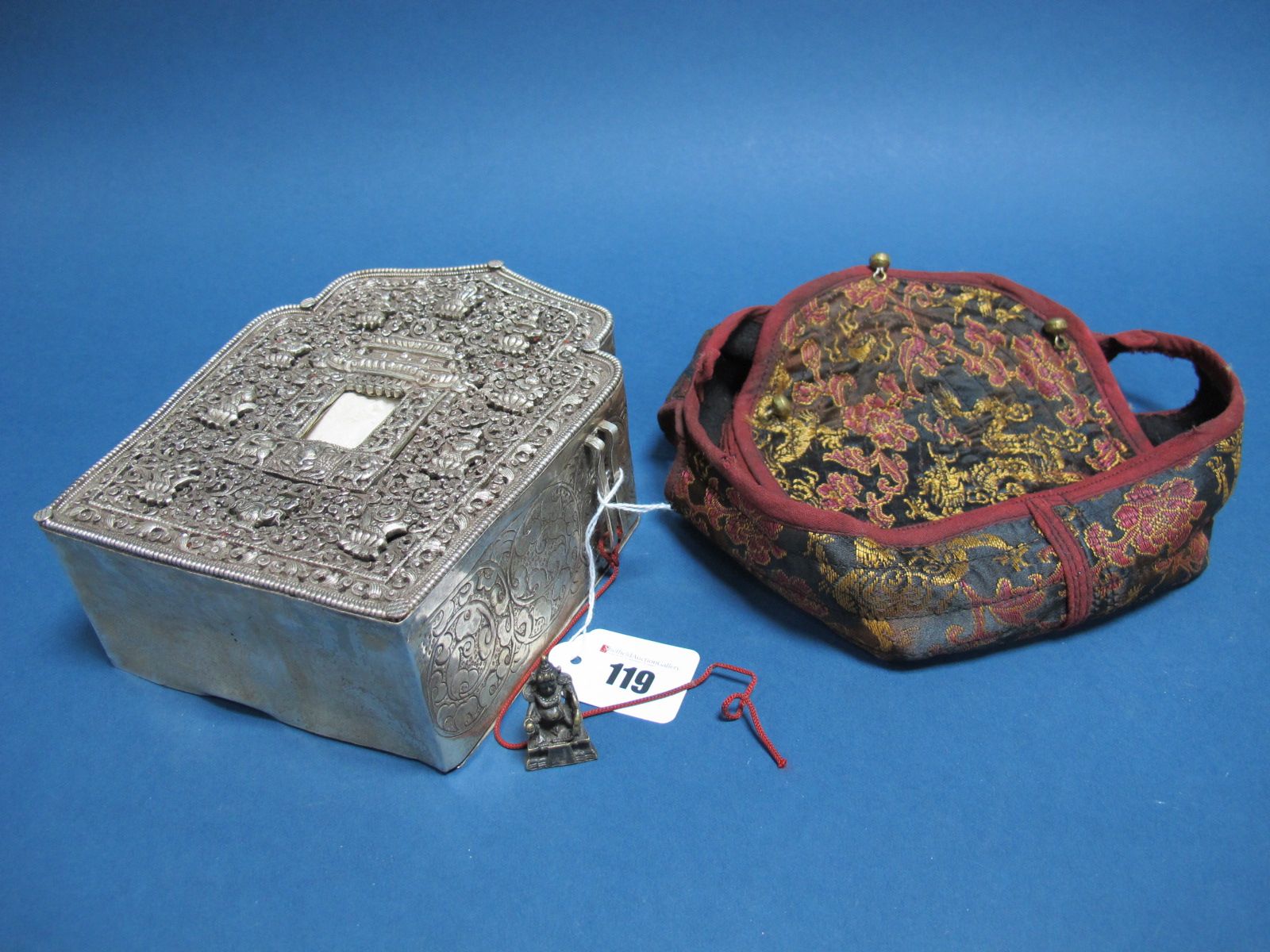 A Chinese Box, of shaped design, allover detailed in relief to the front, the side with strap