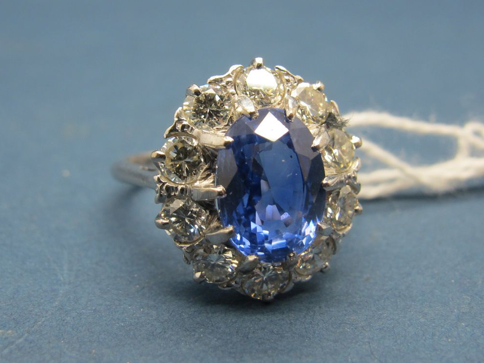 A Large Sapphire and Diamond Cluster Ring, the central (9mm) oval sapphire claw set, within claw set