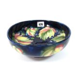 A 1930's Moorcroft Pottery Footed Bowl, painted in the Leaf and Berry pattern against a dark blue
