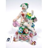 An XIX Century Bow Porcelain Figure of "Summer", the seated cupid raised upon a scrolling floral
