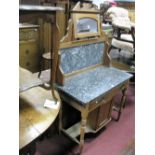 An Early XX Century Walnut Washstand, with a central mirror, grey marble back and top, over cupboard