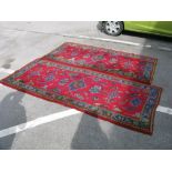 A Pair of Turkish wool Rugs, with a red ground and multicoloured stylised flowers, 241 x 111cm.