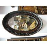 A XIX Century Oval Bevelled Wall Mirror, in stained wooden frame with oak leaf decoration.