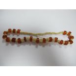 A Late XIX Century String of Amber and Ivory Beads, part carved in the from of flowers, 23cm long.