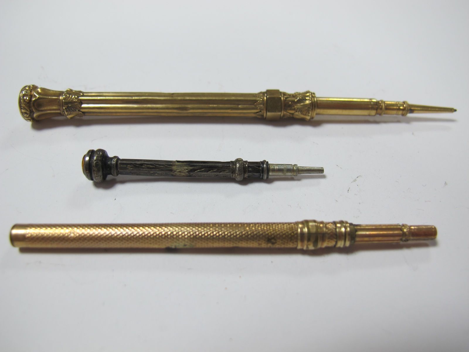 A Sliding Pencil, with hardstone inset end, a miniature hallmarked silver example and another (