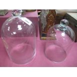 Two Graduated Glass Display Domes, overal heights 27cm, 23cm. (2)