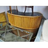 A 1970's Bamboo Kidney Shaped Bar, with a black top, three internal shelves, with foot rest.