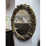 An Oval Wall Mirror, in a deep relief gilt encrusted foliate surround, 55 x 47cm.