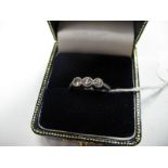 A Three Stone Diamond Ring, the brilliant cut stones semi collet set between inset shoulders.