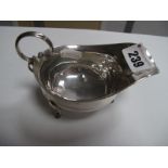 A Hallmarked Silver Sauce Boat, with reeded scroll handle, on three hoof feet (marks rubbed).