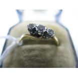 A Three Stone Diamond Ring, the graduated old and single cut stones illusion set between crossover
