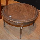 A round oak coffee table, with brown leather top under glass protector,