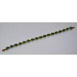 A 9ct gold and peridot tennis style bracelet, set with 17 oval cut peridots, 9k stamped to clasp, 7.