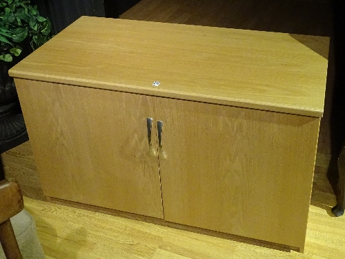 A modern pale oak style cupboard unit, with two cupboard doors enclosing shelved interior,