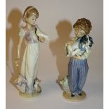 Two Lladro figures, in the form of a boy holding puppy, and a girl with dove and kitten,