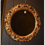 A circular gilt mirror, with elaborate foliate mouldings to frame and bevelled glass to centre,