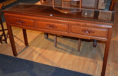 A Chinese hardwood serving table, the three short drawers to top, with carved foliate handles,