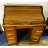 An oak roll top desk, with tambour shutter enclosing fitted drawers and pigeon holes,