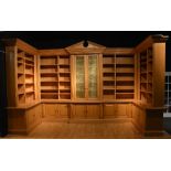 A large bespoke light oak bookcase, with open sections enclosing shelves above panelled doors,