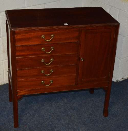 A mahogany music cabinet, with five drawers opposite a panelled door,