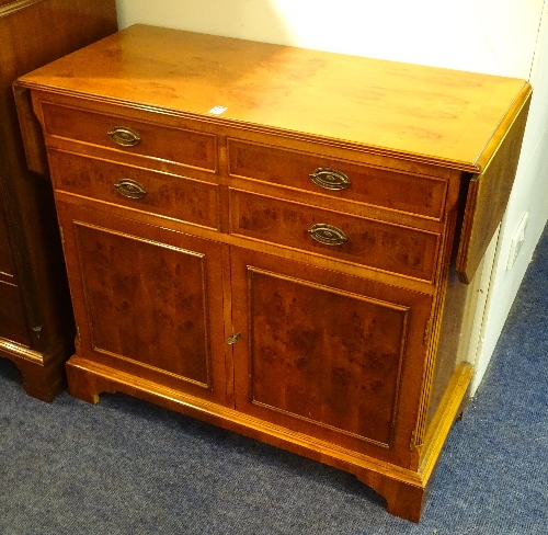 A modern yew wood cupboard, the drop leaves above two sets of two small drawers and two doors,