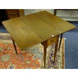 An oak drop leaf table, with drawer to end, raised on tapering supports with brass castors,