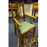 An Arts & Crafts oak elbow chair, the arm rests terminating with scrolls,