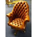 A leather hide buttonback swivel library armchair, raised on wood supports with castors,