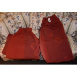 A pair of red fabric curtains, decorated with floral panels,