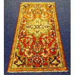 A Hamadan rug, with central floral motif and further floral panels on red ground,