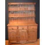 A pine kitchen dresser, the top section with open shelves,