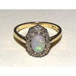 An 18ct gold opal and diamond ring, the central cabochon opal surrounded by 10 round cut diamonds,