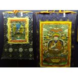 Two Tibetan thangkas depicting Buddhist deities, colourfully decorated with vibrant silks,