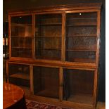 A large oak bookcase, with dentil cornice above three large glazed doors enclosing shelved interior,