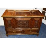 An oak dower chest, with hinged top above carved panels and two small drawers,