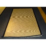 A modern Hessian rug, bound with black edging,